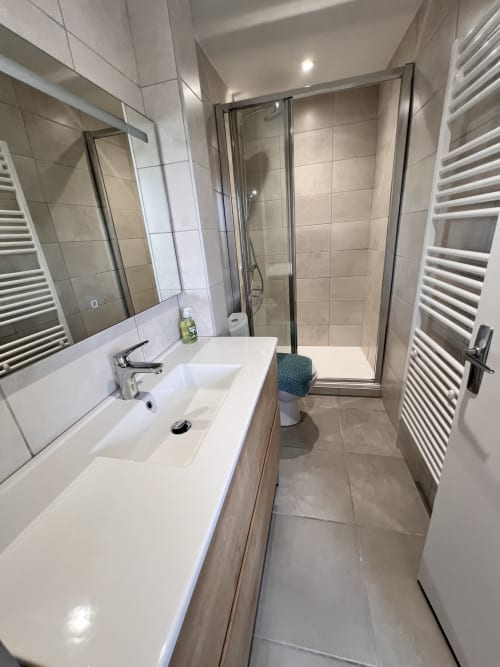 Salle de bain moderne du gîte Le Restaurant du Port, Saint Pierre de Boeuf : lavabo, miroir, douche et sèche-serviettes électrique