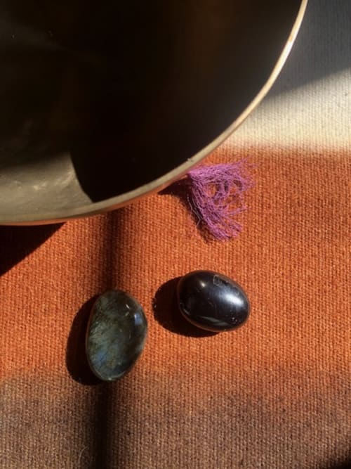 Two polished stones and purple thread on rust-colored fabric at Domaine de l'Ocrerie, Pourrain