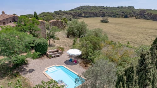 Piscine Finques Garcia Enrich avec parasol blanc et transats avec vue sur les champs et forêts de la campagne de Palafrugell