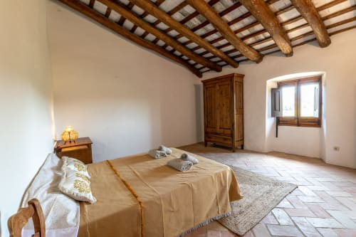 Chambre spacieuse aux poutres en bois apparent, lit, armoire et fenêtre lumineuse à Finques Garcia Enrich, Palafrugell
