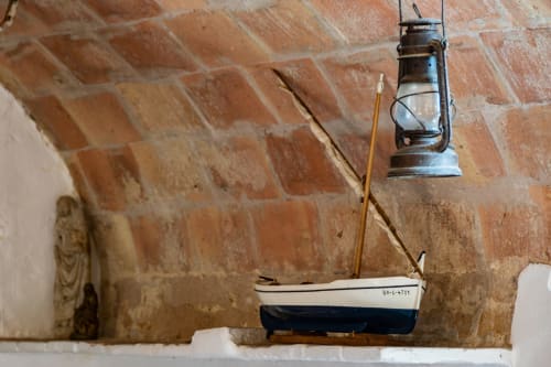 Décoration murale nautique chez Finques Garcia Enrich à Palafrugell avec un petit voilier et une lanterne vintage