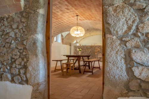 Passage en pierre menant à la salle à manger avec table et chaises en bois chez Finques Garcia Enrich, Palafrugell