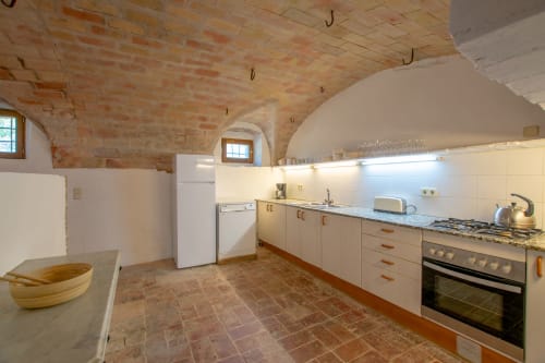 Cuisine rustique aux voûtes de brique chez Finques Garcia Enrich à Palafrugell avec meubles crème et équipements modernes