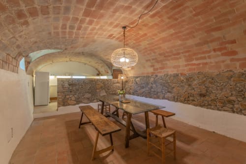 Salle à manger rustique voûtée en briques aux Finques Garcia Enrich à Palafrugell avec table en bois et suspension tressée