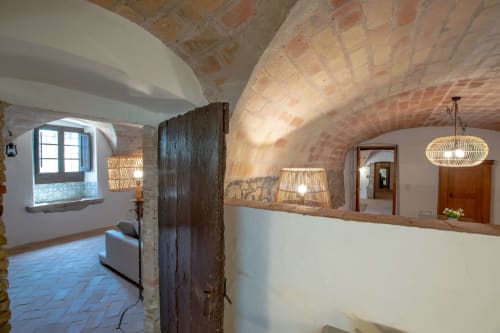 Couloir voûté rustique aux briques apparentes, poutres en bois et luminaires en osier tressé à l'hôtel Finques Garcia Enrich