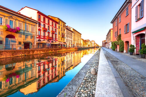 Colorful historic buildings along Navigli canal in Rozzano, Italy, reflecting in calm water