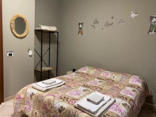 Cozy bedroom at Navigli Affittacamere in Rozzano with patterned bedding, gold mirror, and decorative wall art