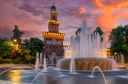 Sforza Castle illuminated at dusk with fountains in Piazza Castello, near Navigli Affittacamere in Rozzano, Milan