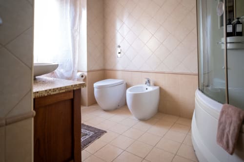 Modern bathroom at Navigli Affittacamere in Rozzano with toilet, bidet, and sink fixtures on tiled walls