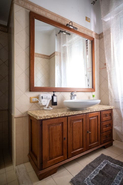 Modern bathroom with wooden vanity, round vessel sink, and framed mirror at Casa Linda in Rozzano