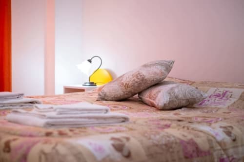 Accogliente camera da letto presso Navigli Affittacamere a Rozzano con cuscini decorati e lampada gialla