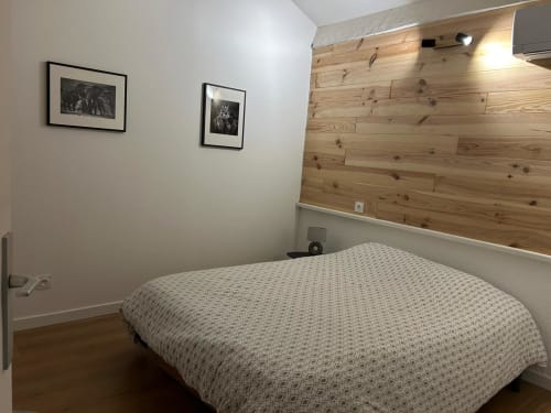 Chambre moderne au Mazet Cavalaire à Cavalaire-sur-Mer avec mur accent en bois, lit et œuvres d'art encadrées
