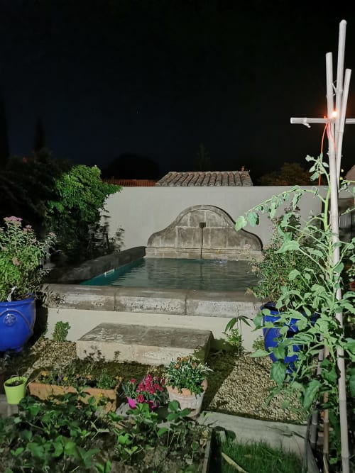 La piscine du jardin Le Cabanon du Clos la nuit, avec ses plantes en fleur et son architecture en pierre à Isle sur la Sorgue