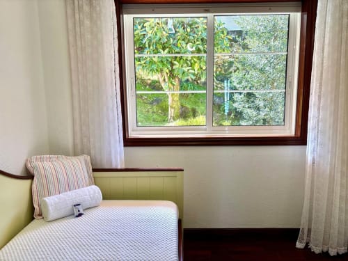 Habitación luminosa con vista al mar en Holibai Baiona, con cama de almohada rayada, cabecero verde y gran ventana