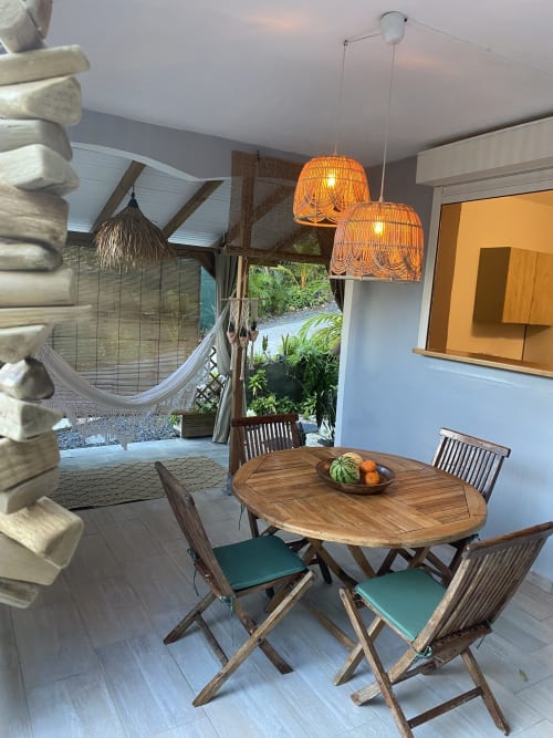 Terrasse couverte avec coin repas, face à la cuisine avec fenêtre passe-plat pratique. Vue sur jardin et patio cosy avec hamac.