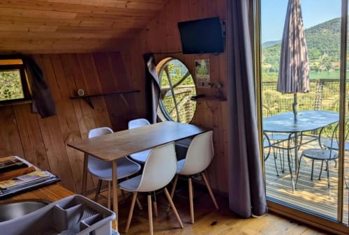 Intérieur moderne de la cabine au Belvédère avec table à manger, TV et vues panoramiques de la vallée par les portes vitrées