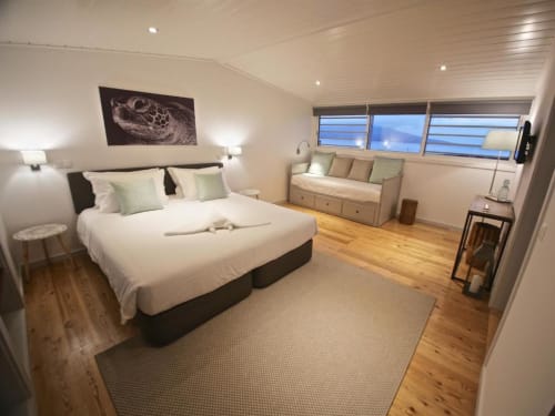 A serene and stylish minimalist bedroom featuring a neutral-toned bed with cozy linens, complemented by a wooden side table
