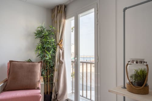 Luminosa habitación de estudio en Formentera Especial con asientos rosa, plantas en maceta y balcón con vistas al puerto de La Savina
