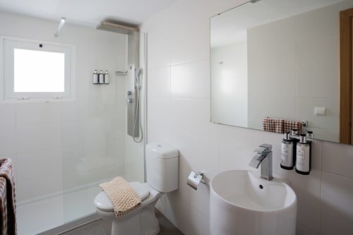 Baño moderno y blanco en Formentera Especial con ducha tipo walk-in, lavabo redondo y servicios