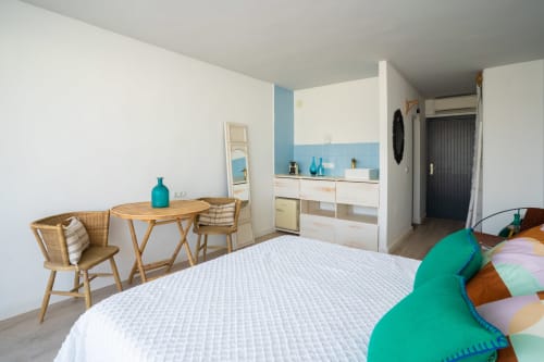 Estudio moderno en Formentera Especial con cama blanca, escritorio de madera, cocina americana y toques turquesa en La Savina