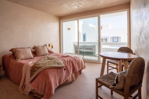 Estudio Luna en Formentera Especial con ropa de cama rosa, sillas de mimbre, mesa redonda y balcón con vistas al mar en La Savina