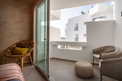 Balcón del estudio Formentera Especial Luna con muebles de mimbre, vistas al mar y arquitectura moderna