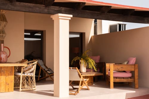 Terraza moderna en Formentera Especial con muebles de madera, cojines rosas y vistas al mar en La Savina