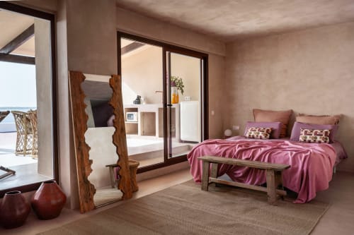 Dormitorio del apartamento Formentera Especial con ropa de cama rosa, espejo de madera, balcón con vistas al mar y baño en suite en La Savina