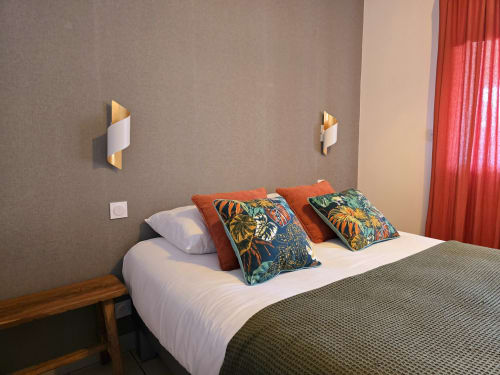 Chambre élégante du gîte Relais des Iles avec lit blanc, coussins colorés, appliques dorées et rideaux rouges