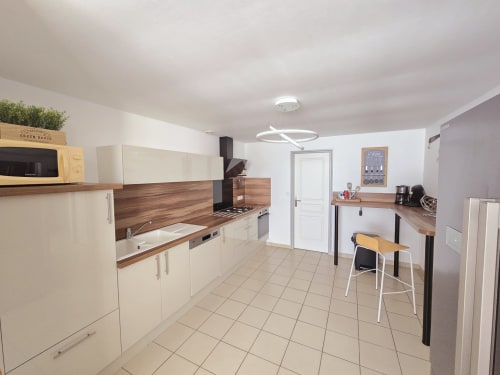 Modern equipped kitchen in Gîte Les Coquillages cottage at Relais des îles, Saint-Marcouf, with cream cabinetry, wooden