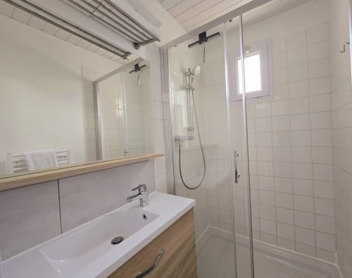 Modern bathroom with walk-in shower, vanity sink, and mirror at Relais des Îles cottage, Saint-Marcouf
