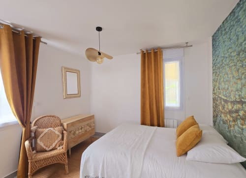 Bright bedroom at Relais des Îles cottage in Saint-Marcouf with white bed, golden curtains, wicker chair, and sea-view