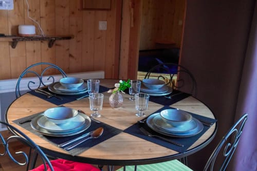 Elegant dining setup at Cabane LA PINEDE villa with blue-rimmed plates, wine glasses, and a small plant centerpiece on a