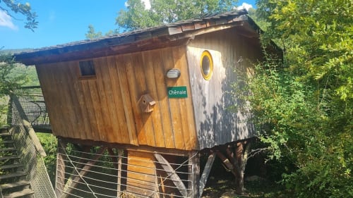 Capanna in legno La Chenaie con oblò giallo a Cabanes du Belvédère, Serrières-sur-Ain, circondata dal verde