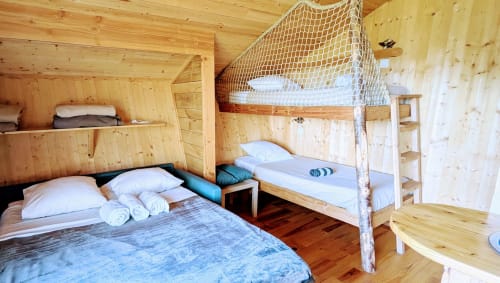 Camera da letto in cabana con letto a castello, letto matrimoniale, biancheria bianca e interno rustico in pino alle Cabanes et lodges du Belvédère