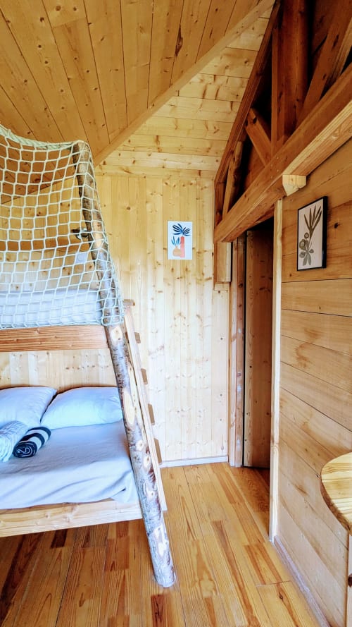 Accogliente camera in cabina di legno con letto a soppalco, biancheria blu e arte moderna alle Cabanes du Belvédère, Serrières-sur-Ain