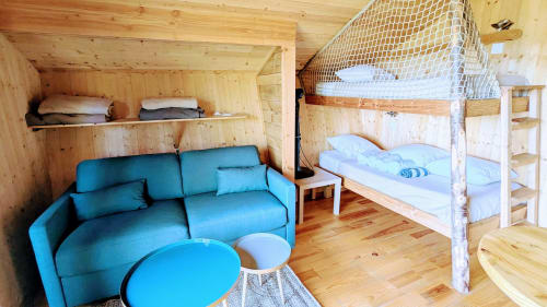 Interno accogliente di cabina in legno con divano blu, letti a castello in soppalco con rete bianca e pareti in legno