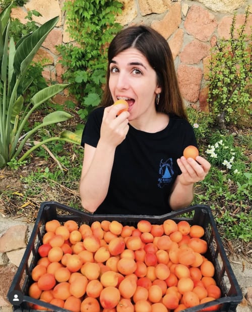 Woman enjoying fresh apricots at Agriturismo Su Barraccu farm in Loceri, Italy