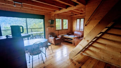 Wooden lodge interior with dining area, living room, terrace overlooking mountains at Cabanes du Belvédère, Serrières-sur-Ain