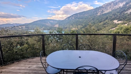 Outdoor dining terrace at Cabanes et lodges du Belvédère with mountain and lake views overlooking Serrières-sur-Ain, France