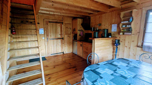 Cozy wooden lodge interior at Cabanes du Belvédère with kitchen, dining area, and rustic furnishings overlooking nature