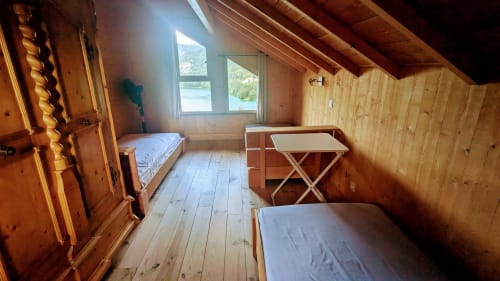 Wooden lodge bedroom with lake view, featuring two beds, desk, and rustic timber interior at Cabanes et lodges du Belvédère