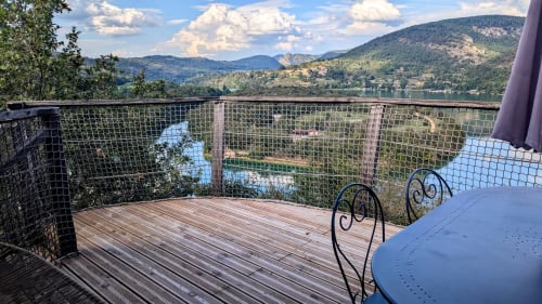 Terrazza in legno con ringhiere in metallo affacciata sul fiume Ain e le montagne alle Cabanes du Belvédère, Serrières-sur-Ain