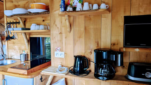 Angolo cottura in cabina di legno con caffettiere, bollitore e stoviglie presso Cabanes et lodges du Belvédère, Serrières-sur-Ain