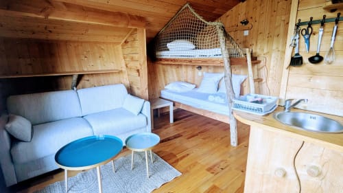 Interno di capanna in legno con divano blu, tavoli da pranzo, letto a baldacchino, angolo cucina e spa