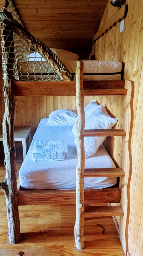 Letti a castello in legno rustico con biancheria bianca in una accogliente capanna presso Cabanes et lodges du Belvédère, Serrières-sur-Ain