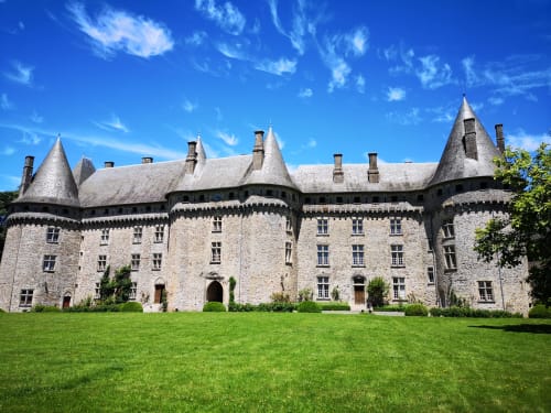 Château Hôtel Saint-Roch avec ses tourelles, façade en pierre, pelouse impeccable sous un ciel bleu à Saint-Ybard, France