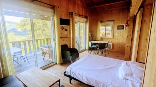 Spaziosa camera di lodge con vista sul lago, interno in legno, letto, zona pranzo e terrazza presso Cabanes et lodges du Belvédère