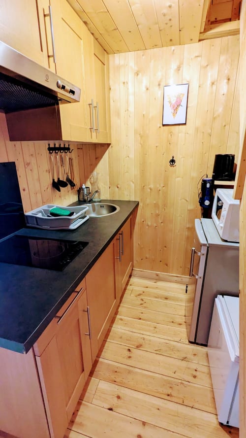 Piccola cucina in legno nella Lodge LE TAILLET di Cabanes et lodges du Belvédère con stufa, lavello ed elettrodomestici