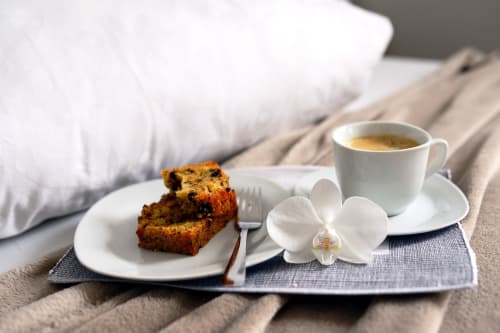 breakfast tray on the bed with coffee, cake and flower